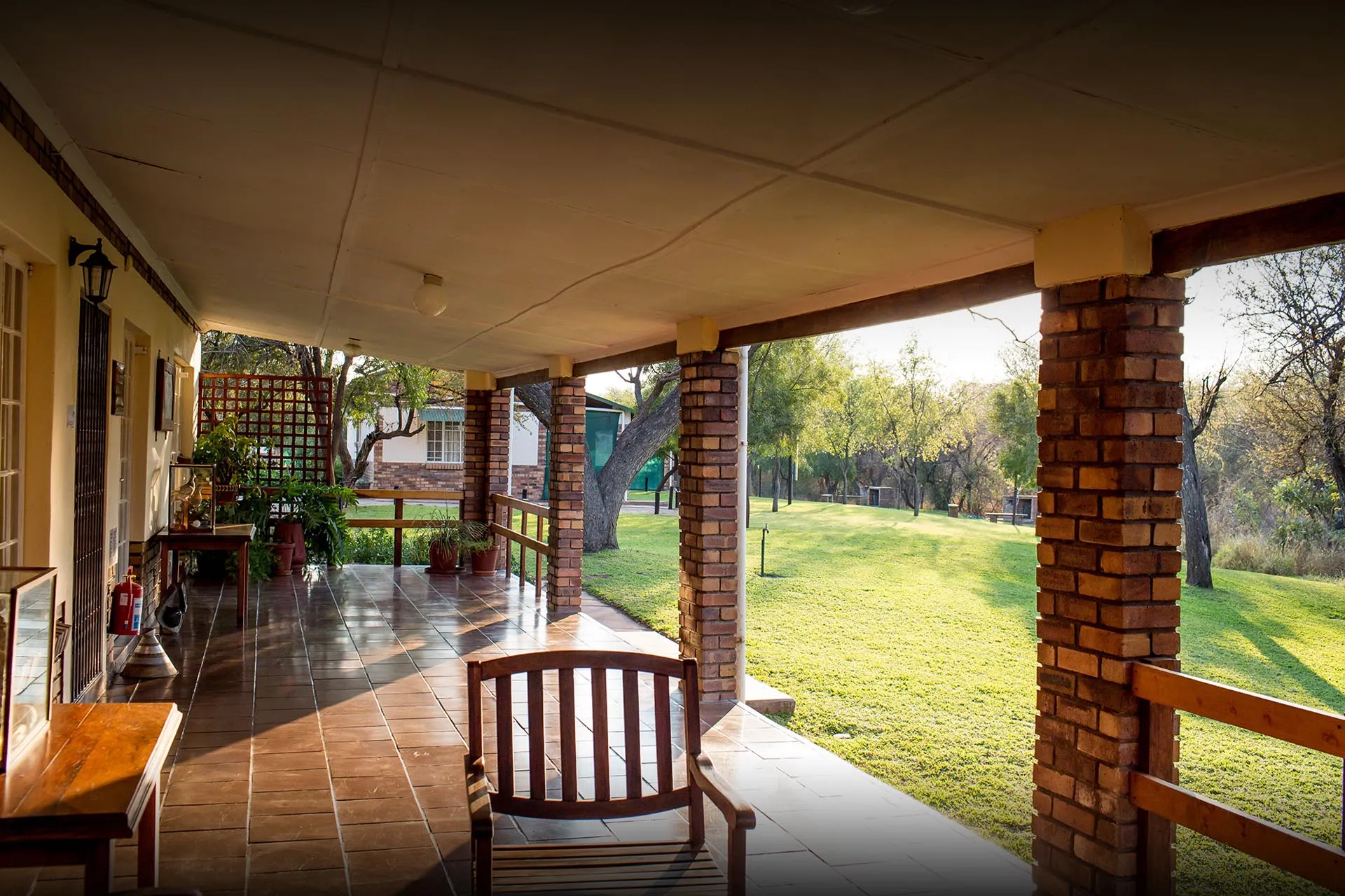 Wooden chair on a covered patio overlooking a green lawn and trees