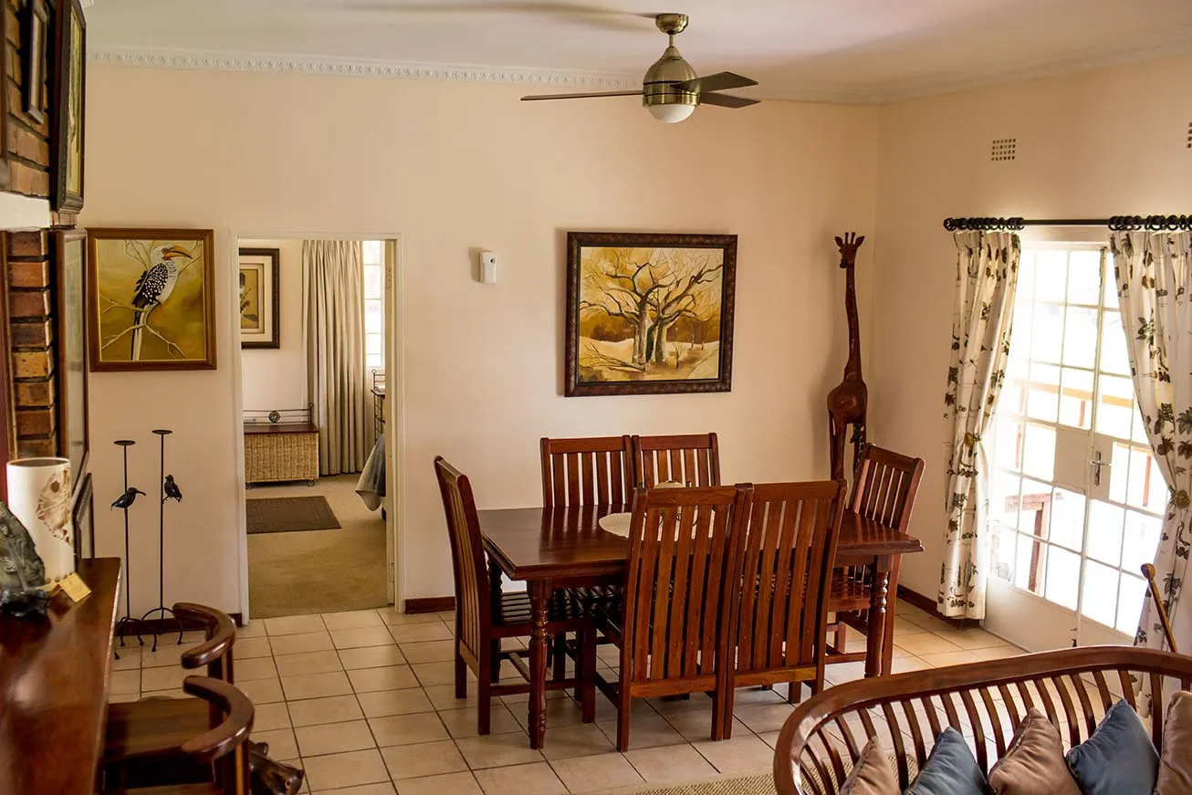 Dining area with wooden table and chairs giraffe statue and artwork on walls