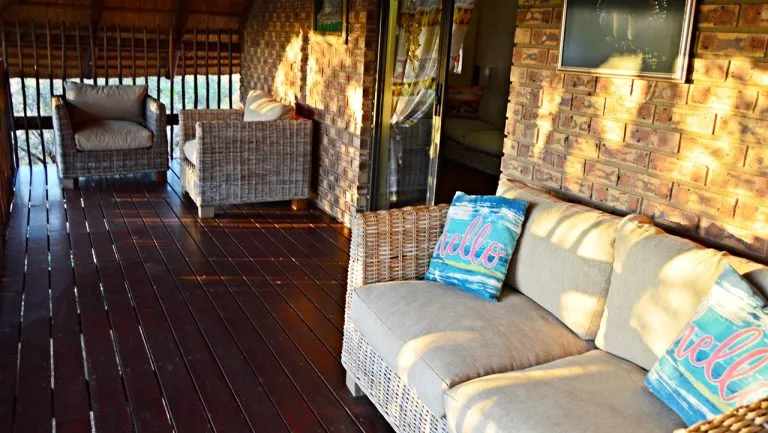 Wicker furniture on a wooden deck with a brick wall background