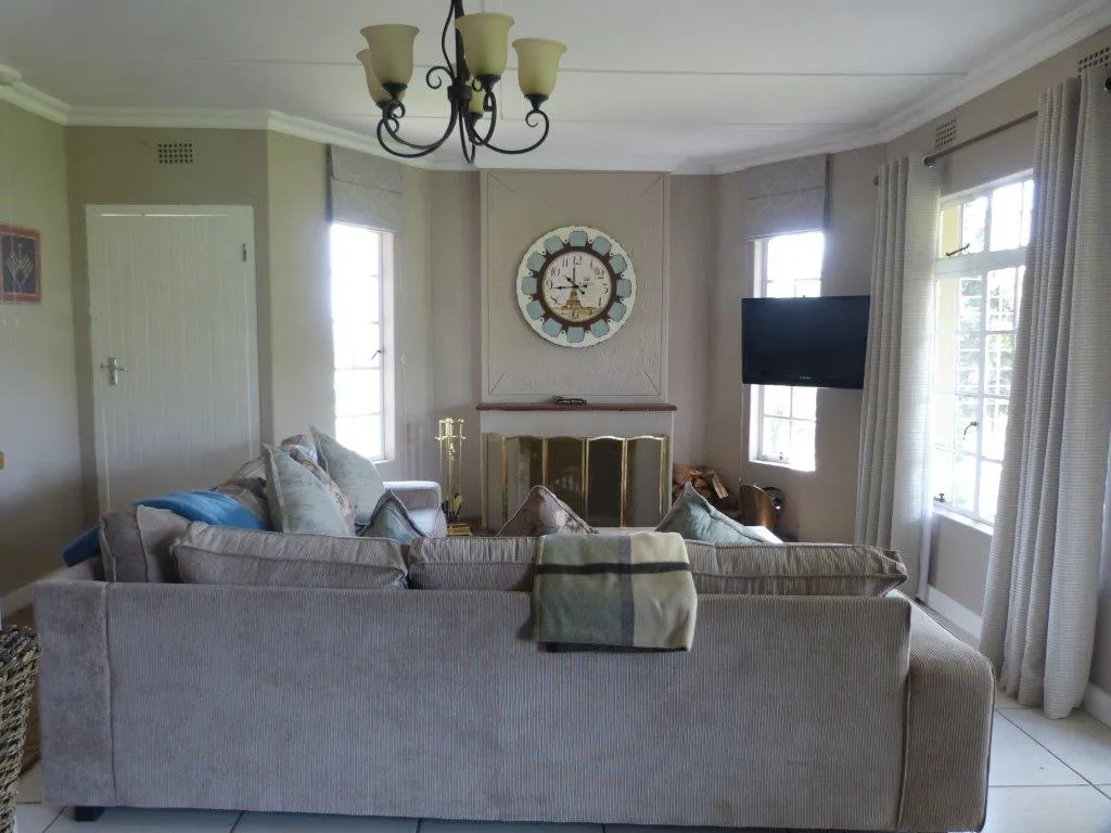 Living room with large sofa TV clock and windows with curtains