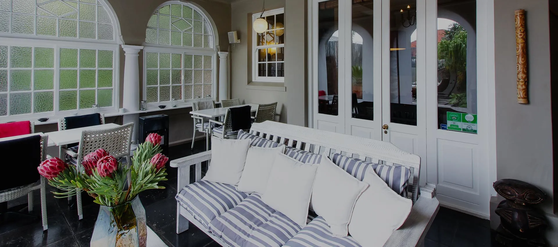 White sofa with striped cushions in a sunlit room with large windows
