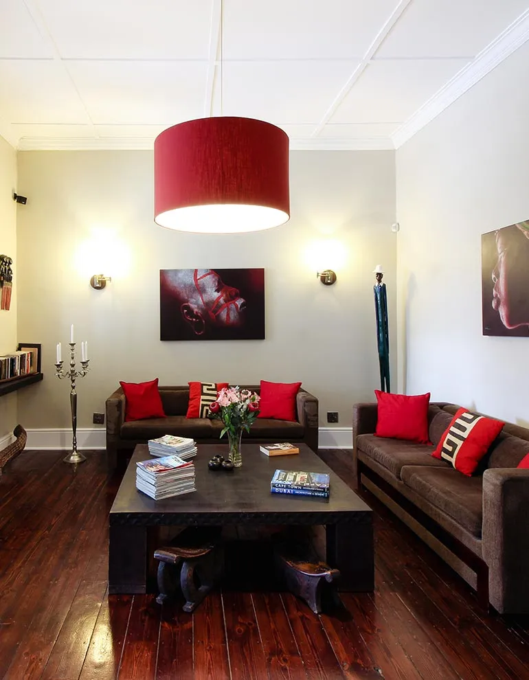 Modern living room with red and brown furniture books and artwork on walls