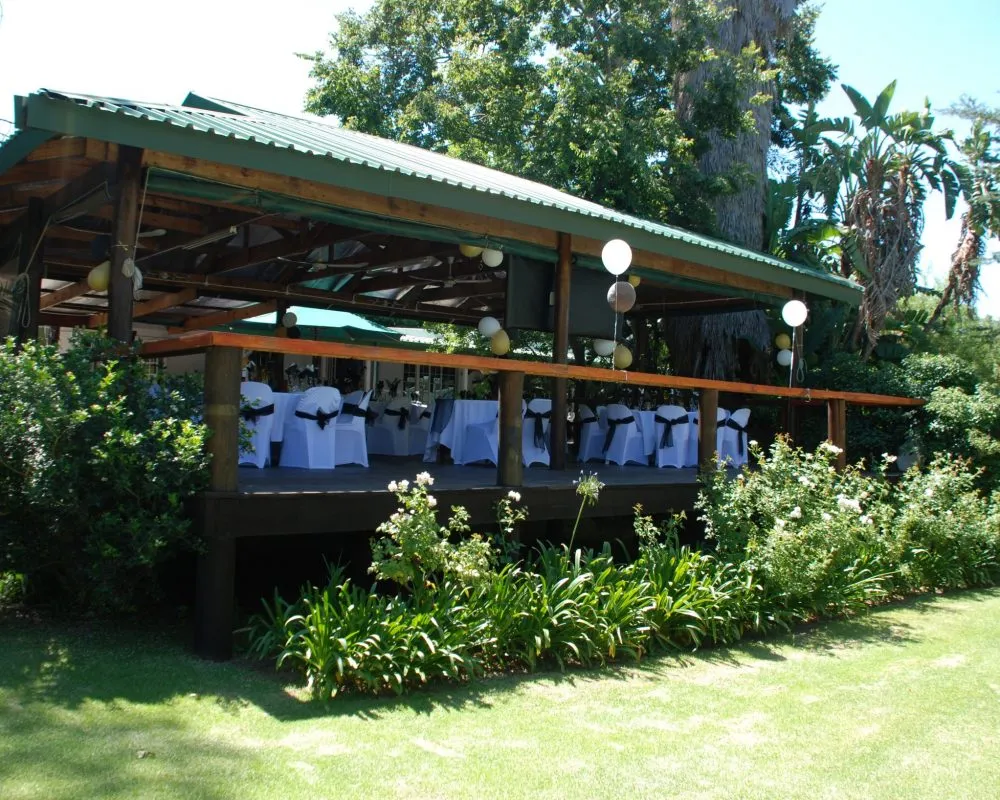 Outdoor event venue with white chairs and tables on a wooden deck