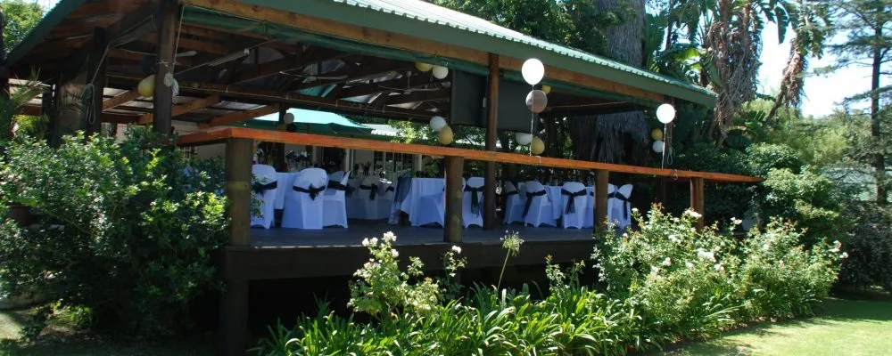 Outdoor event space with tables chairs and white chair covers on a deck