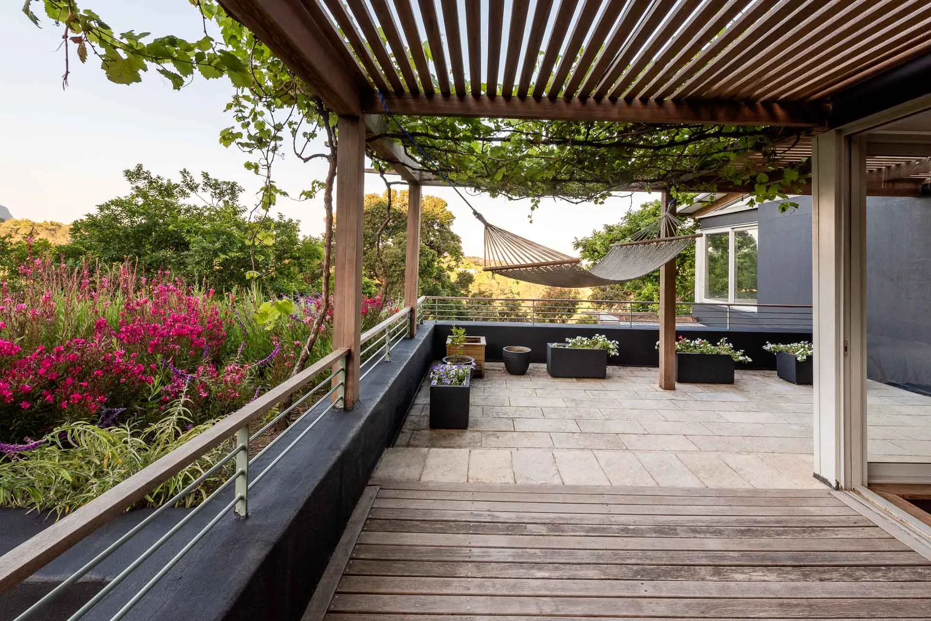 Wooden deck with hammock plants and modern building in background