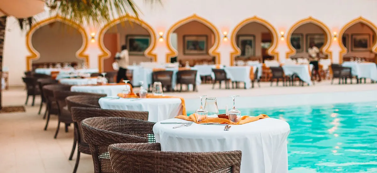 Outdoor dining area with wicker chairs and tables beside a swimming pool