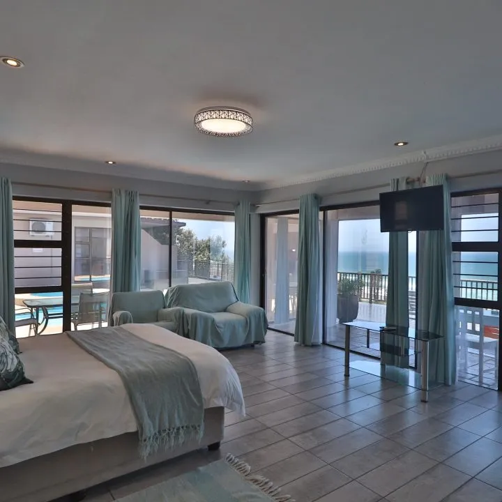 Modern bedroom with large windows ocean view and blue curtains