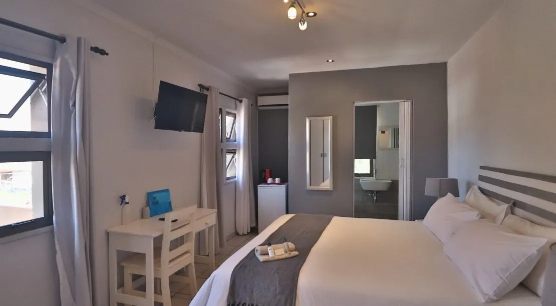 Modern bedroom with bed desk TV and ensuite bathroom