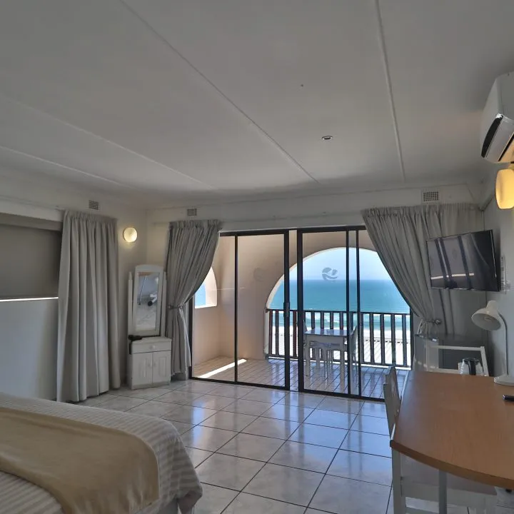 Hotel room with ocean view bed desk and sliding glass doors