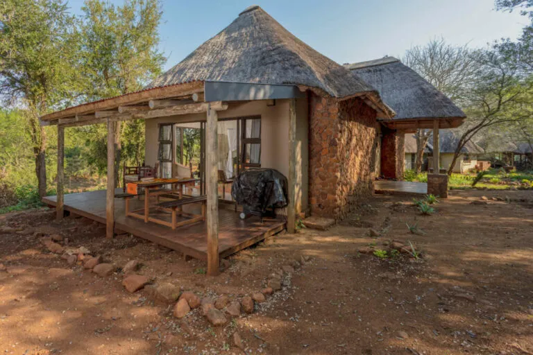 Rustic wooden cabin with a veranda and outdoor seating in a natural setting