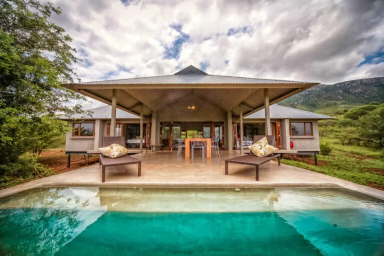 Modern house with pool lounge chairs and scenic mountain backdrop