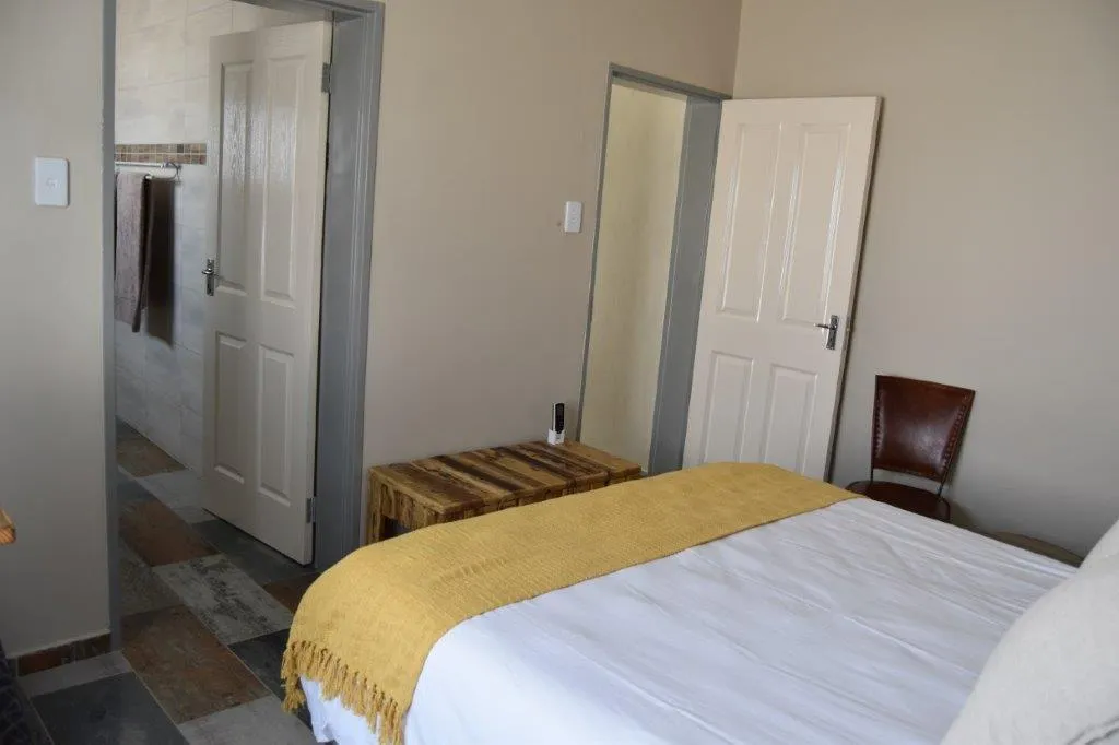 Bedroom with a bed wooden bench and open doors to bathroom and hallway