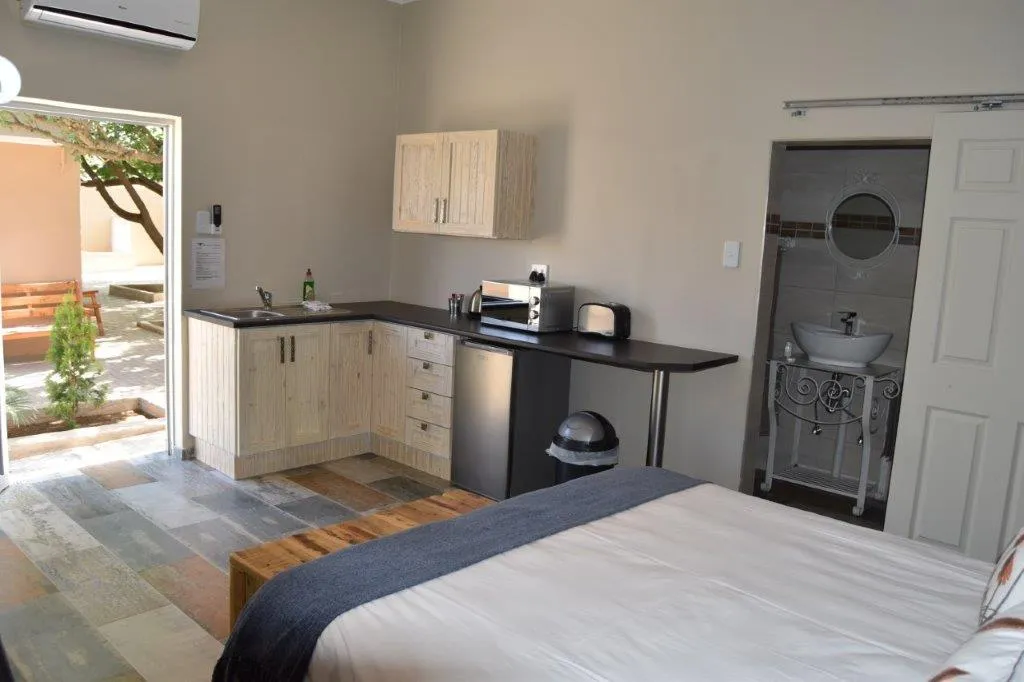 Studio apartment with kitchenette bed and bathroom visible through an open door