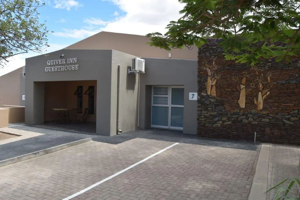 Modern guesthouse entrance with stone wall art and parking area