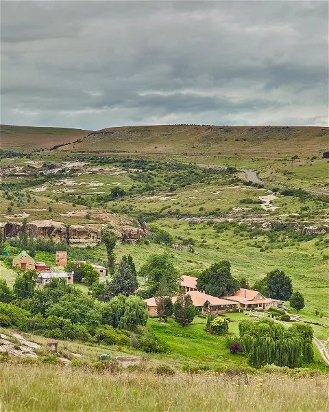Countryside landscape with scattered houses and rolling green hills under a cloudy sky
