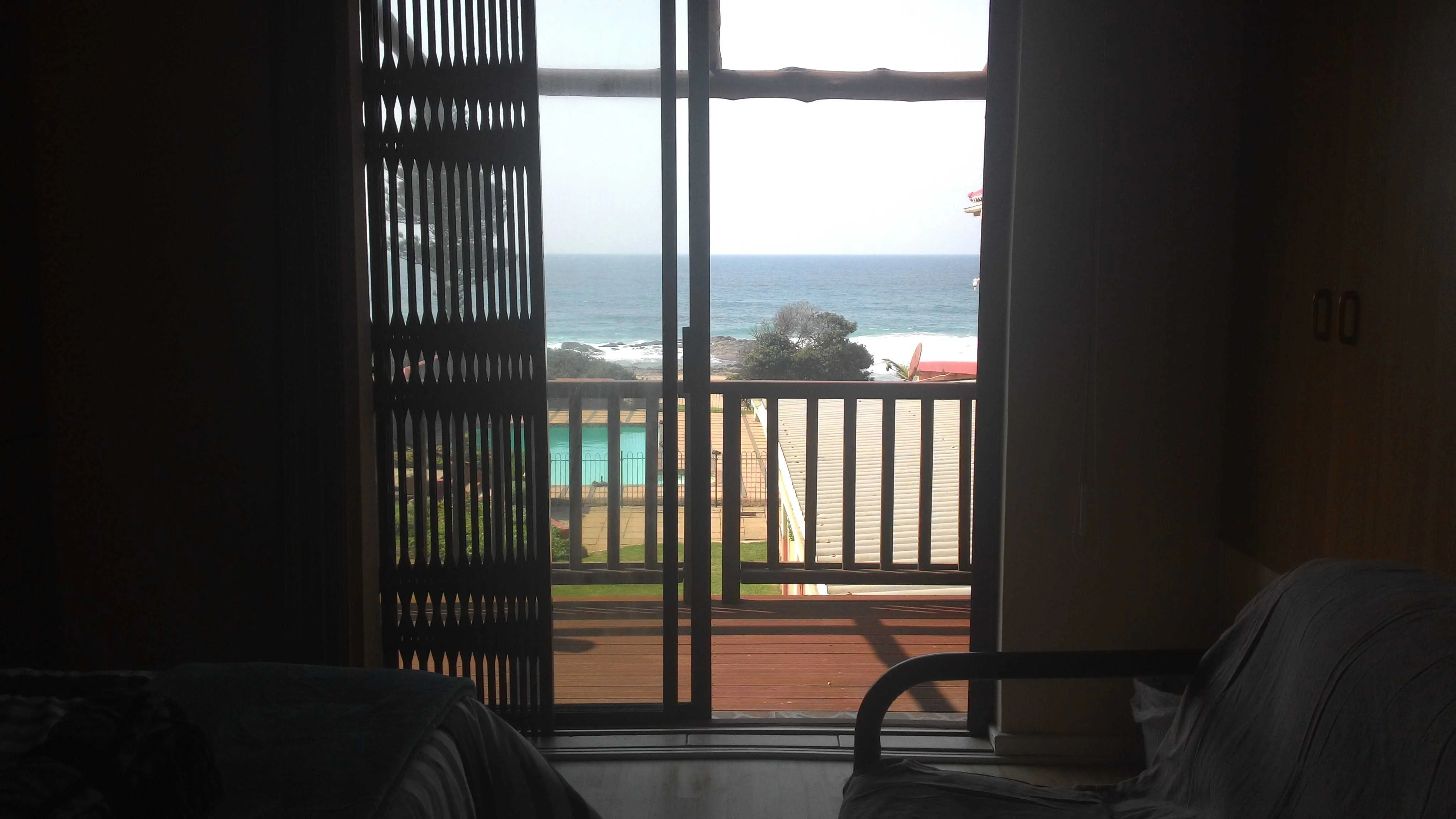 View of ocean and pool from a room with open sliding doors