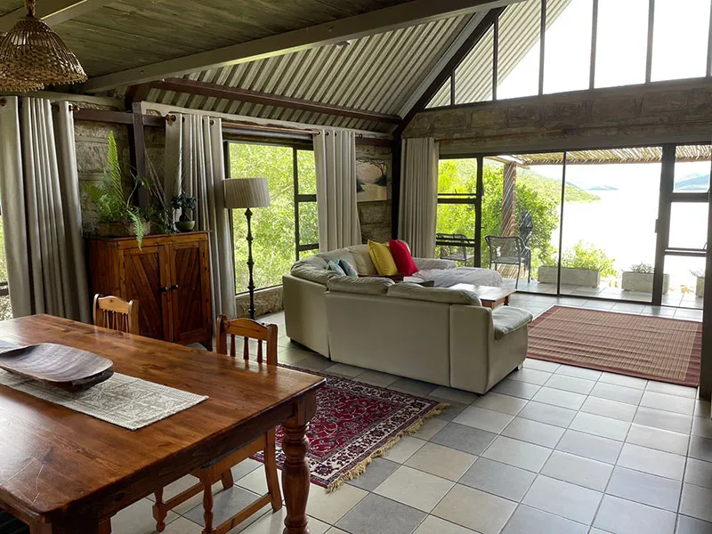 Bright living room with sofa dining table and large windows overlooking water