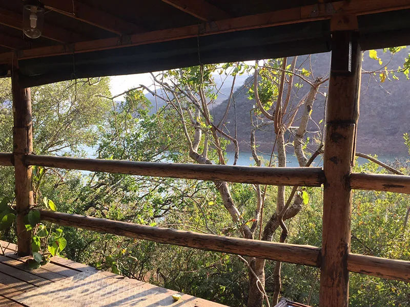 Wooden balcony overlooking a lake with trees and mountains in the background