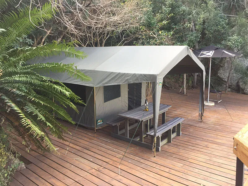 Tent with wooden deck and picnic table in a forested area