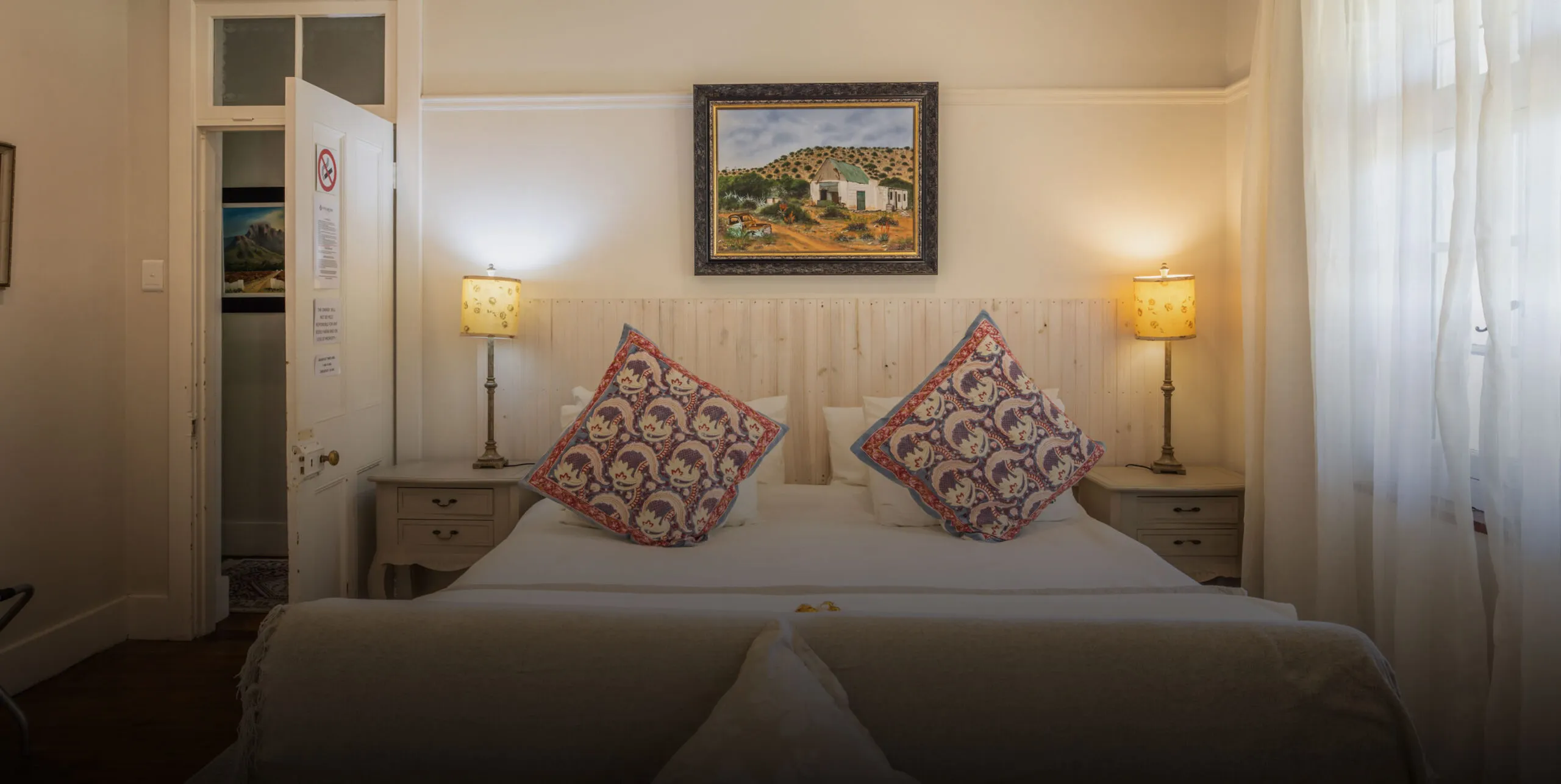 Cozy bedroom with a double bed two lamps and a framed painting