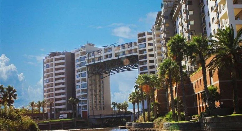 Modern buildings with a large archway palm trees and a clear blue sky