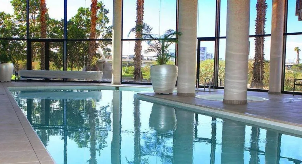 Indoor pool with large windows potted plants and palm trees outside