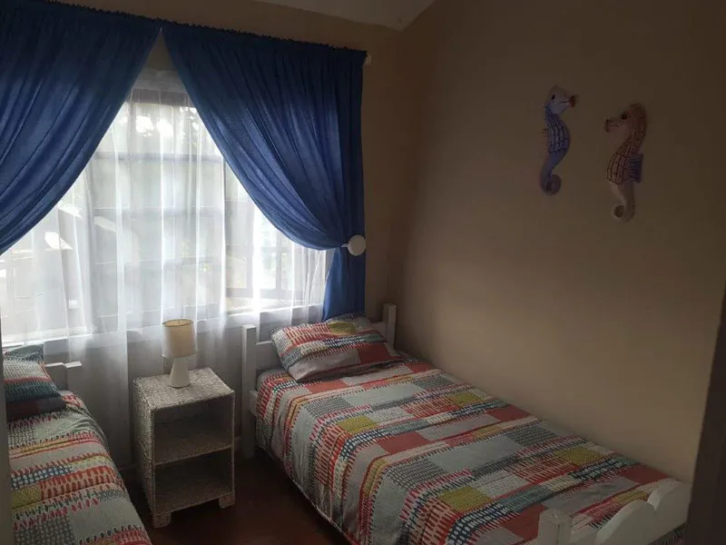 Two single beds in a bedroom with blue curtains and seahorse wall decorations