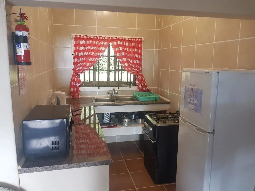 Small kitchen with red checkered curtains white tiles and basic appliances