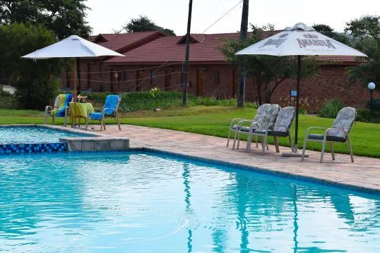 Swimming pool with lounge chairs umbrellas and a grassy area in the background