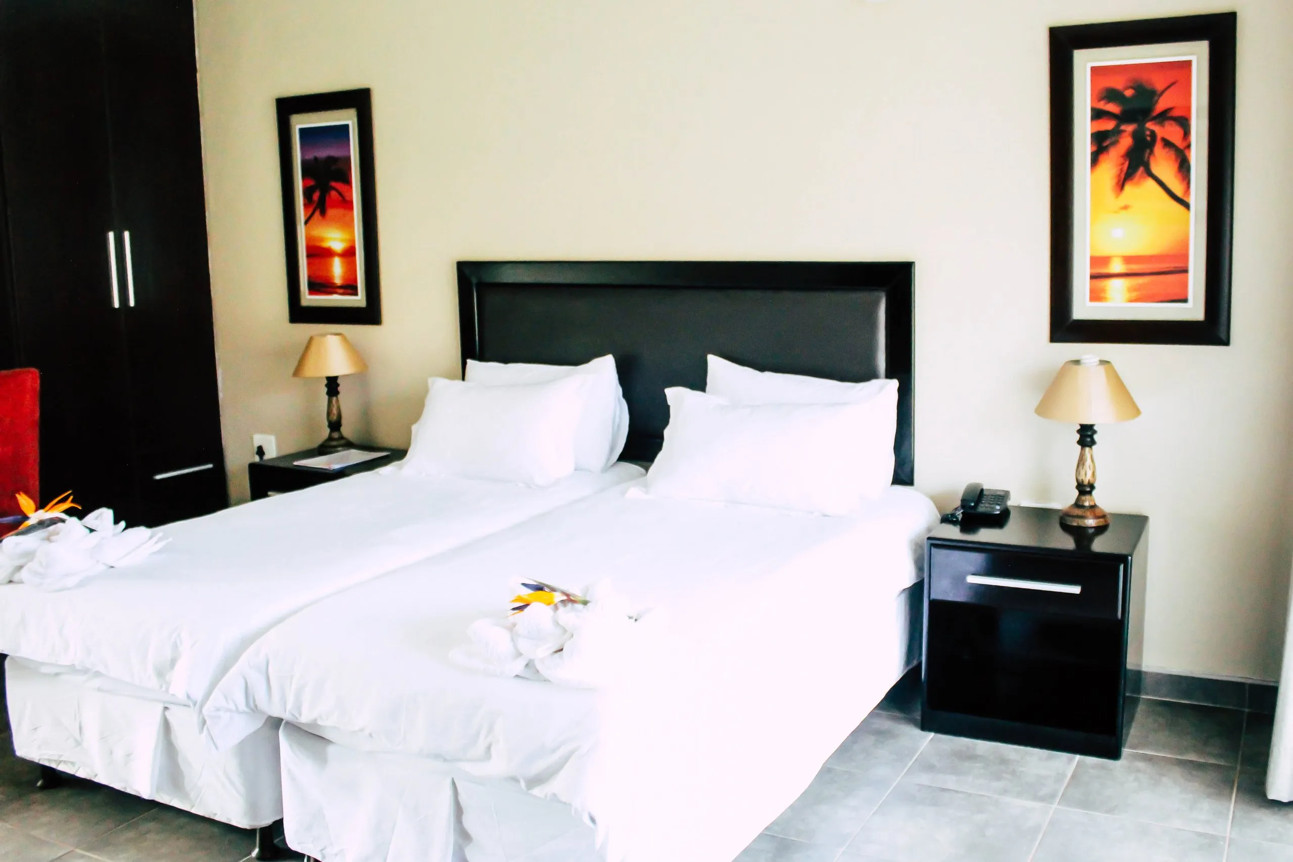 Two neatly made beds in a bedroom with tropicalthemed wall art