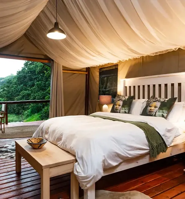 Cozy bed in a tent with draped ceiling wooden floor and forest view