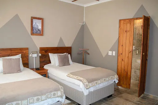 Two single beds in a bedroom with wooden furniture and geometric wall design