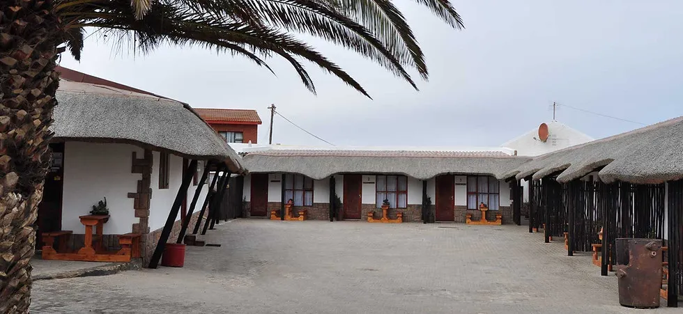 Courtyard with thatchedroof buildings and palm tree overcast sky