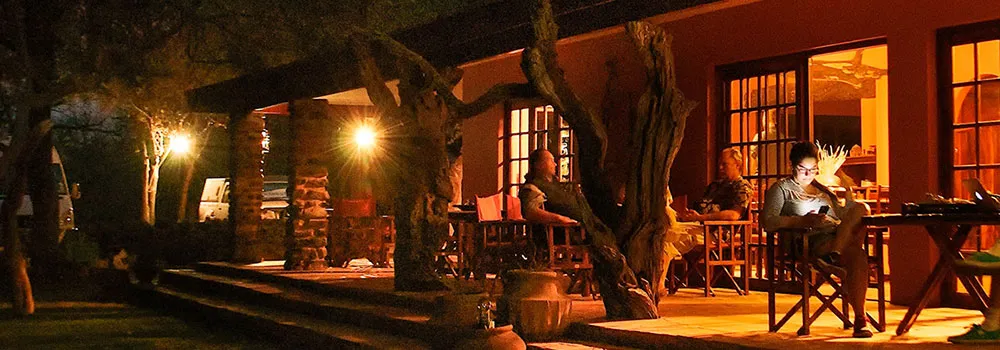 Evening scene at a warmly lit outdoor patio with people sitting and relaxing