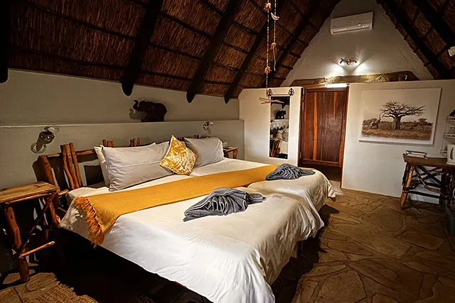 Cozy bedroom with two beds wooden furniture and a thatched ceiling