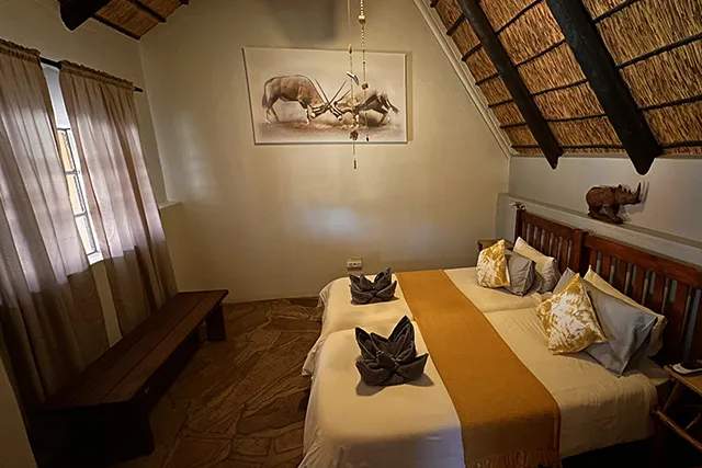 Cozy bedroom with two beds wooden bench and animal artwork on the wall