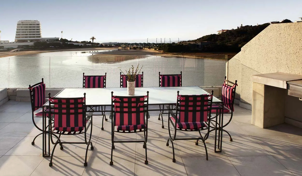 Outdoor dining area with red and black chairs table and water view