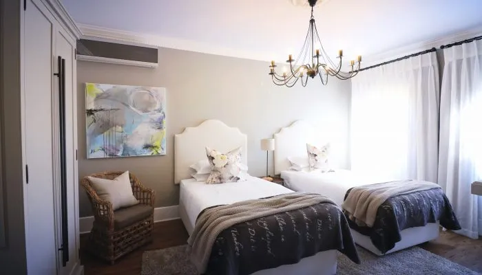 Two beds in a bright bedroom with a chandelier and abstract wall art
