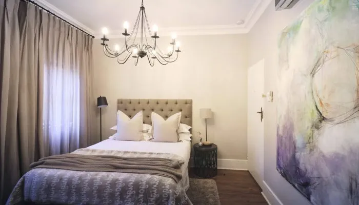Cozy bedroom with a large bed chandelier and abstract wall art
