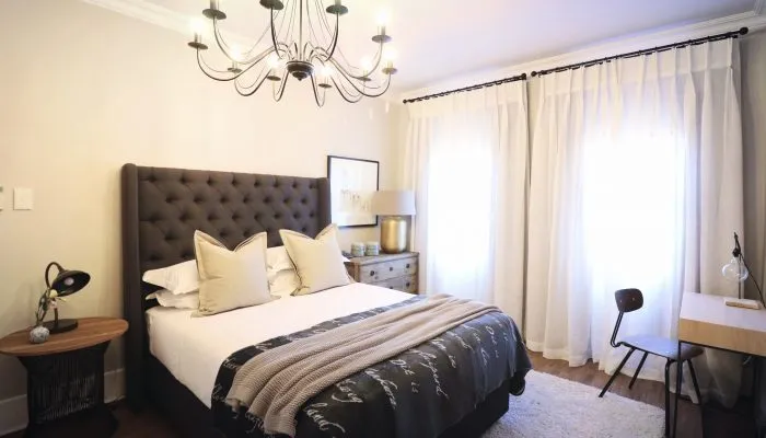 Modern bedroom with large bed nightstand desk and bright window curtains