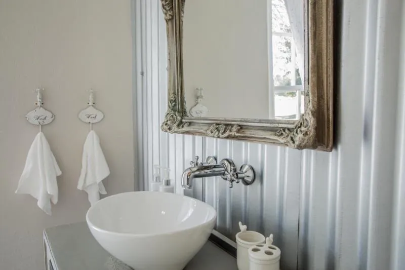 White sink with a vintage mirror in a modern bathroom with towels hanging