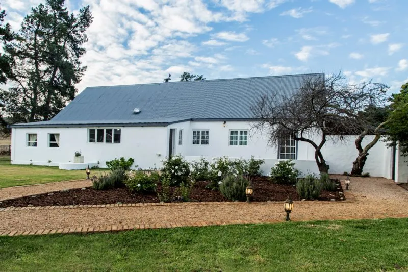 White house with grey roof garden and pathway in a green lawn setting