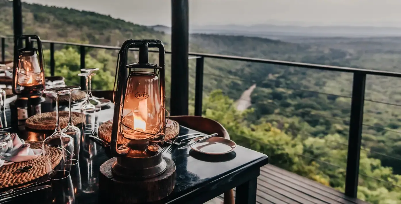 Lanterns on a table with a scenic view of green hills and a river