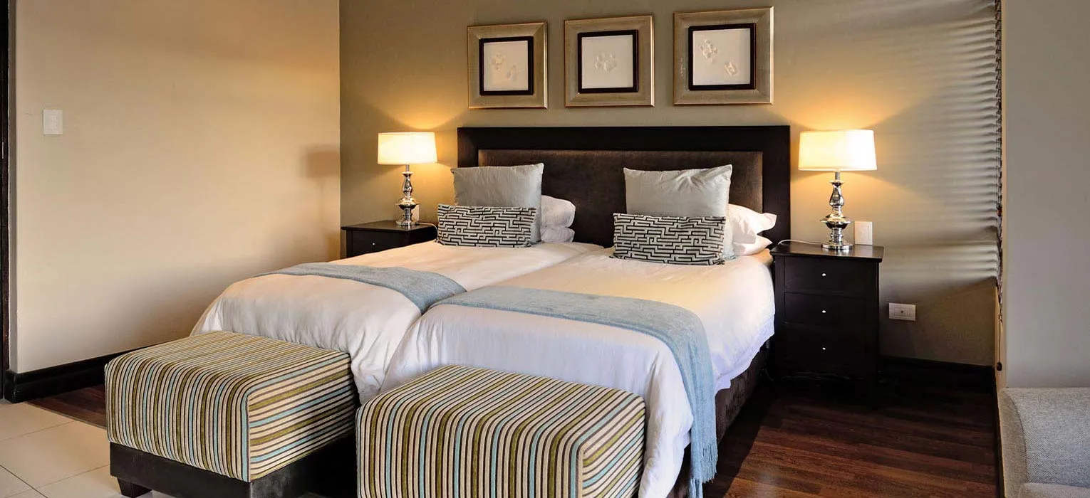 Modern bedroom with large bed bedside tables lamps and striped ottomans