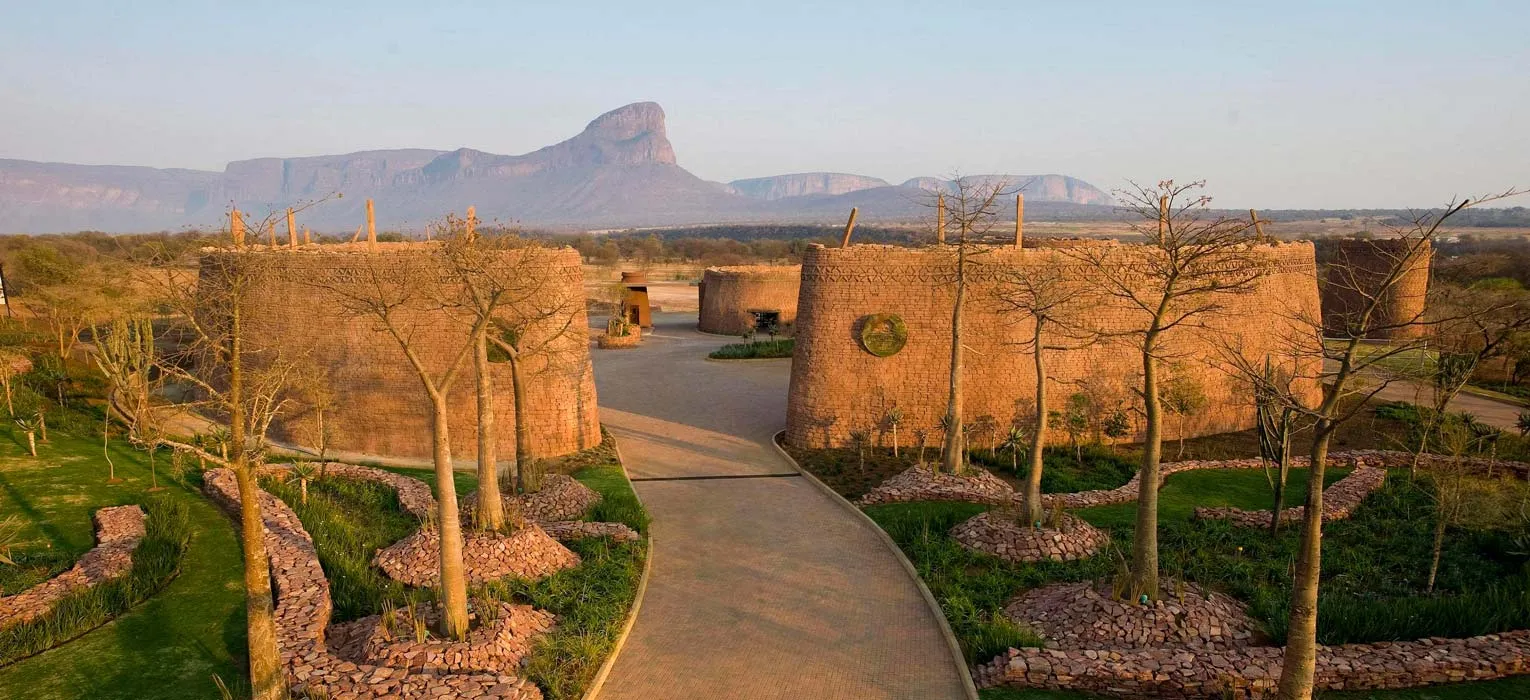 Adobestyle buildings with trees and a pathway in a desert landscape with mountains