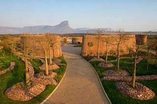 Pathway between two large circular buildings with trees and mountains in background