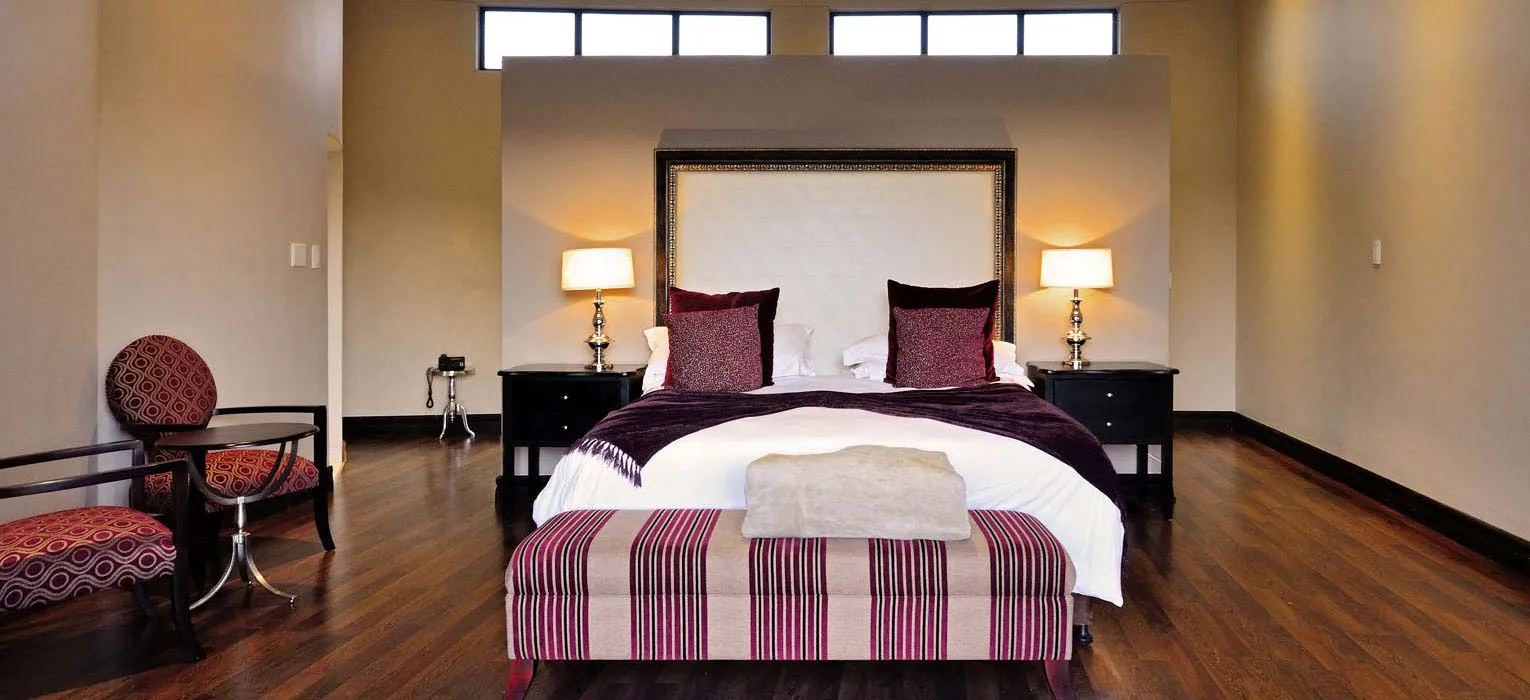 Modern bedroom with large bed striped bench and wooden floor