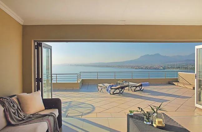 Living room with open doors to a patio with sea and mountain views