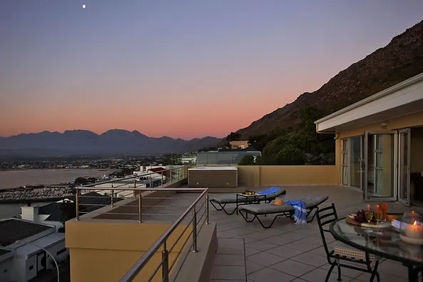 Rooftop patio with lounge chairs dining table and mountain view at sunset