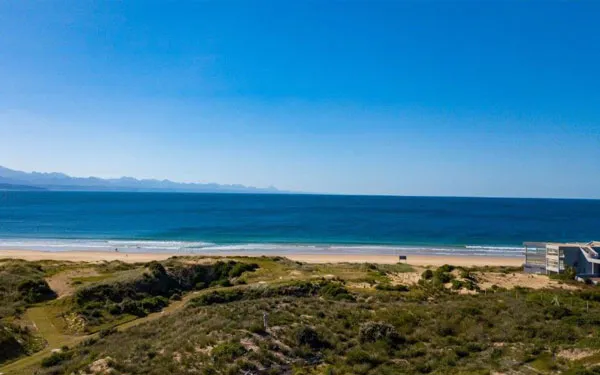 Coastal landscape with sandy beach ocean and dunes under a clear blue sky